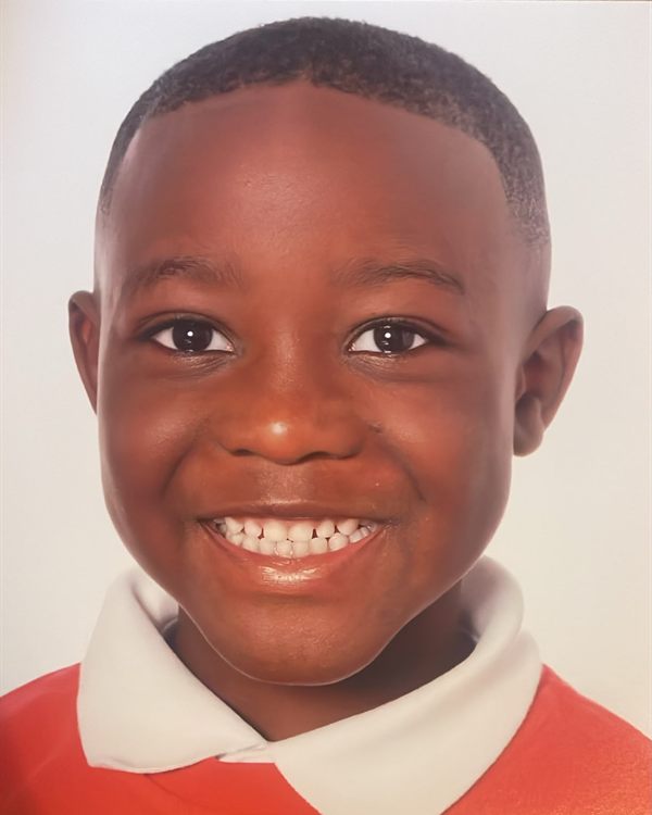 Close-up school portrait of a smiling boy in a red jumper with a white collar