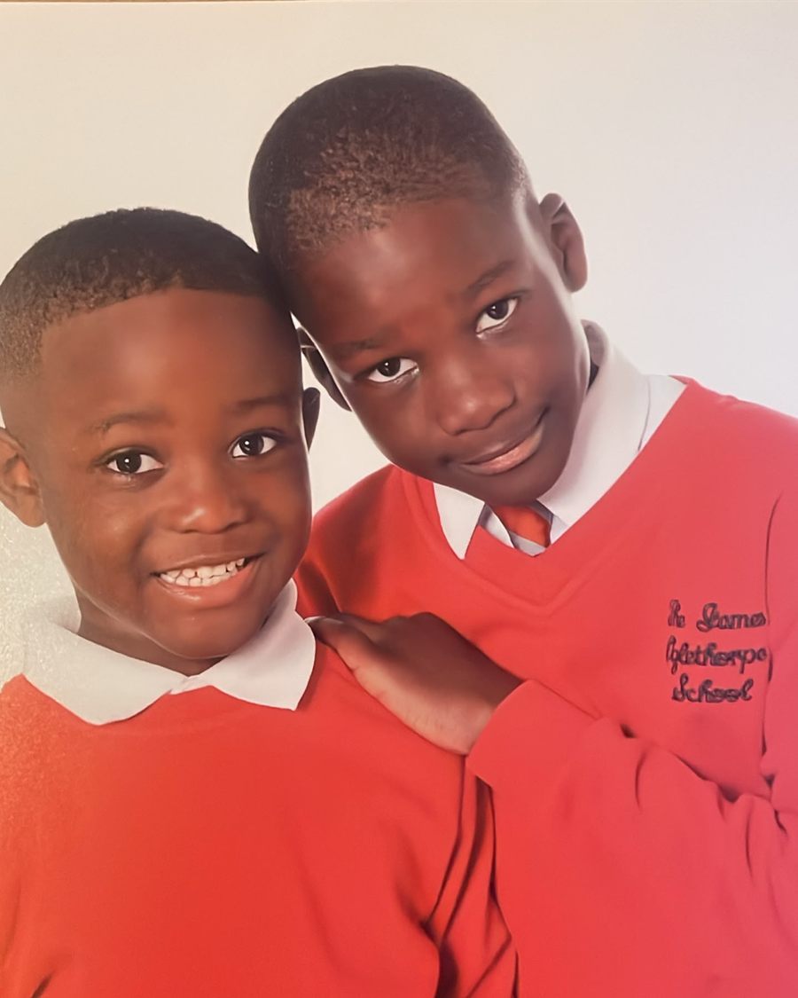 Two brothers in red school jumpers posing together for a portrait