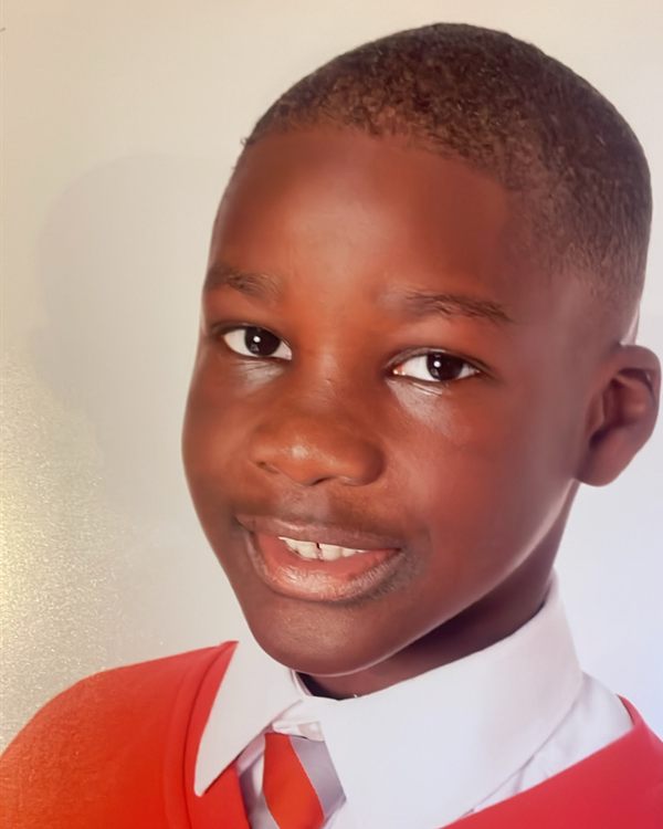 Close-up school portrait of a smiling boy in a red jumper and striped tie