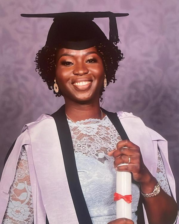 Graduation portrait of a smiling woman in cap and gown holding her certificate